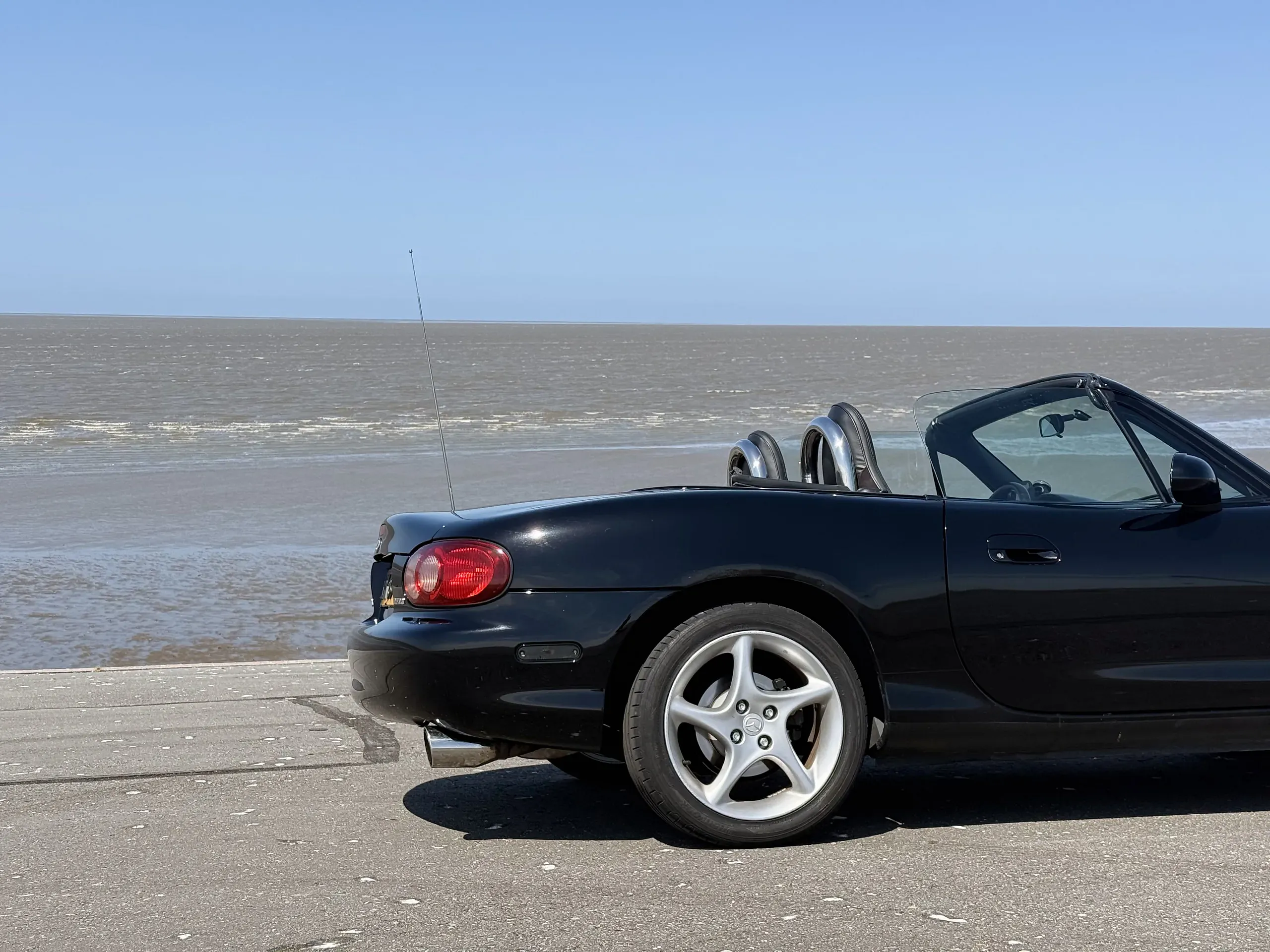 Black Mazda MX-5 parked beside the Wadden Sea